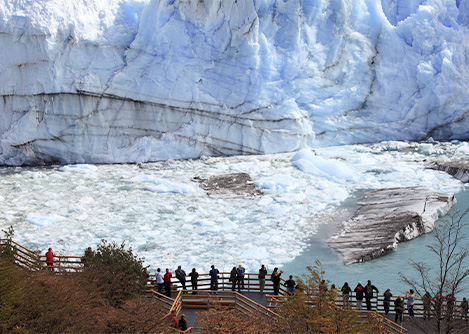 Visitors looking at the massive Perito Moreno glacier from a wooden walkway.