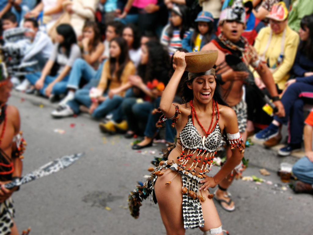 A woman dancing in a parade with a beaded and feathered traditional Amazonian outfit.