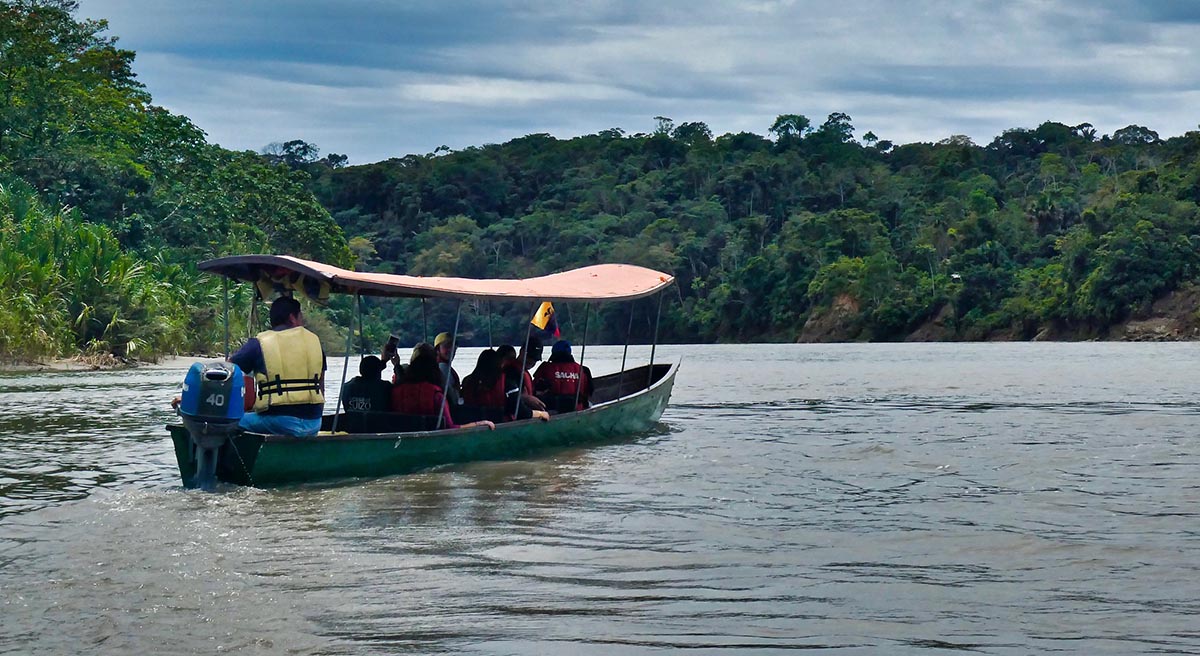 Eight people travel on a small boat in the Amazon, one of the best places to visit in Ecuador.