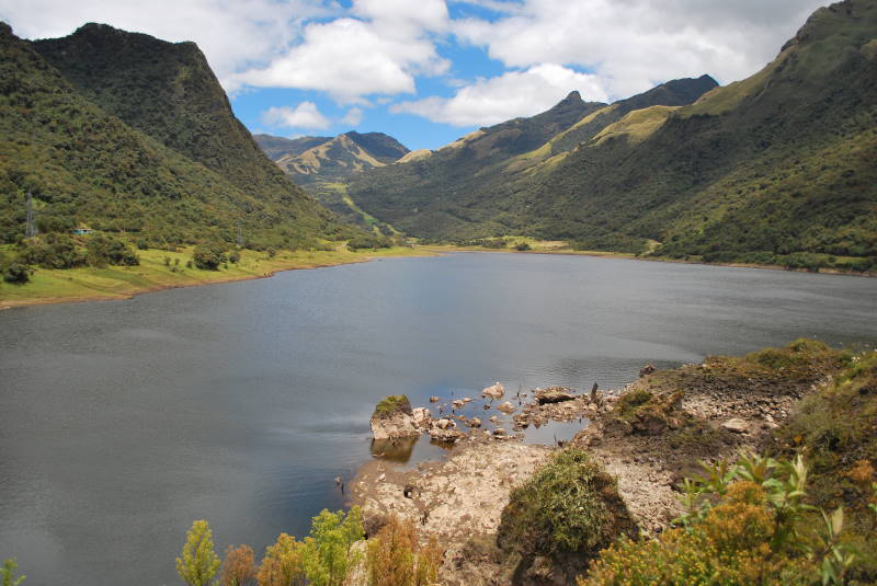 Lake Papallacta, a blue lagoon nestled between several small hills covered in green vegetation.
