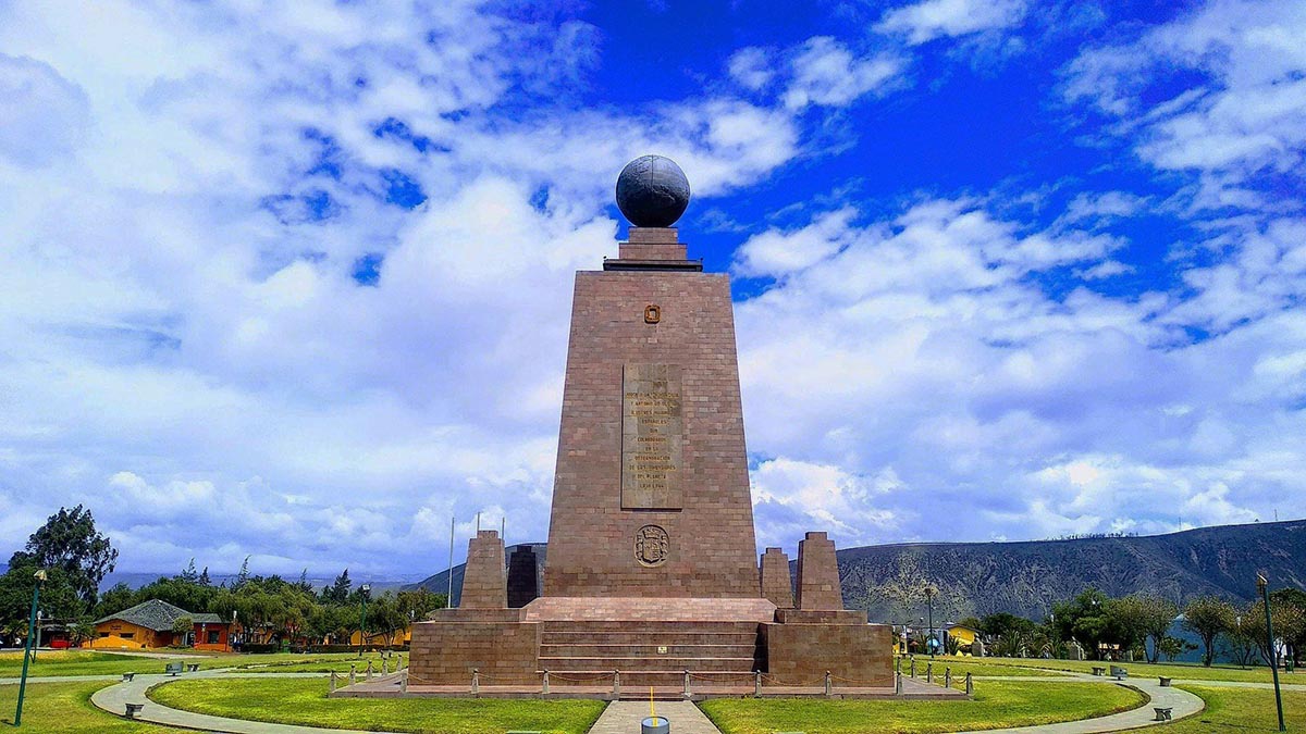 A tall stone monument with a globe placed on top at the equatorial line in Ecuador.