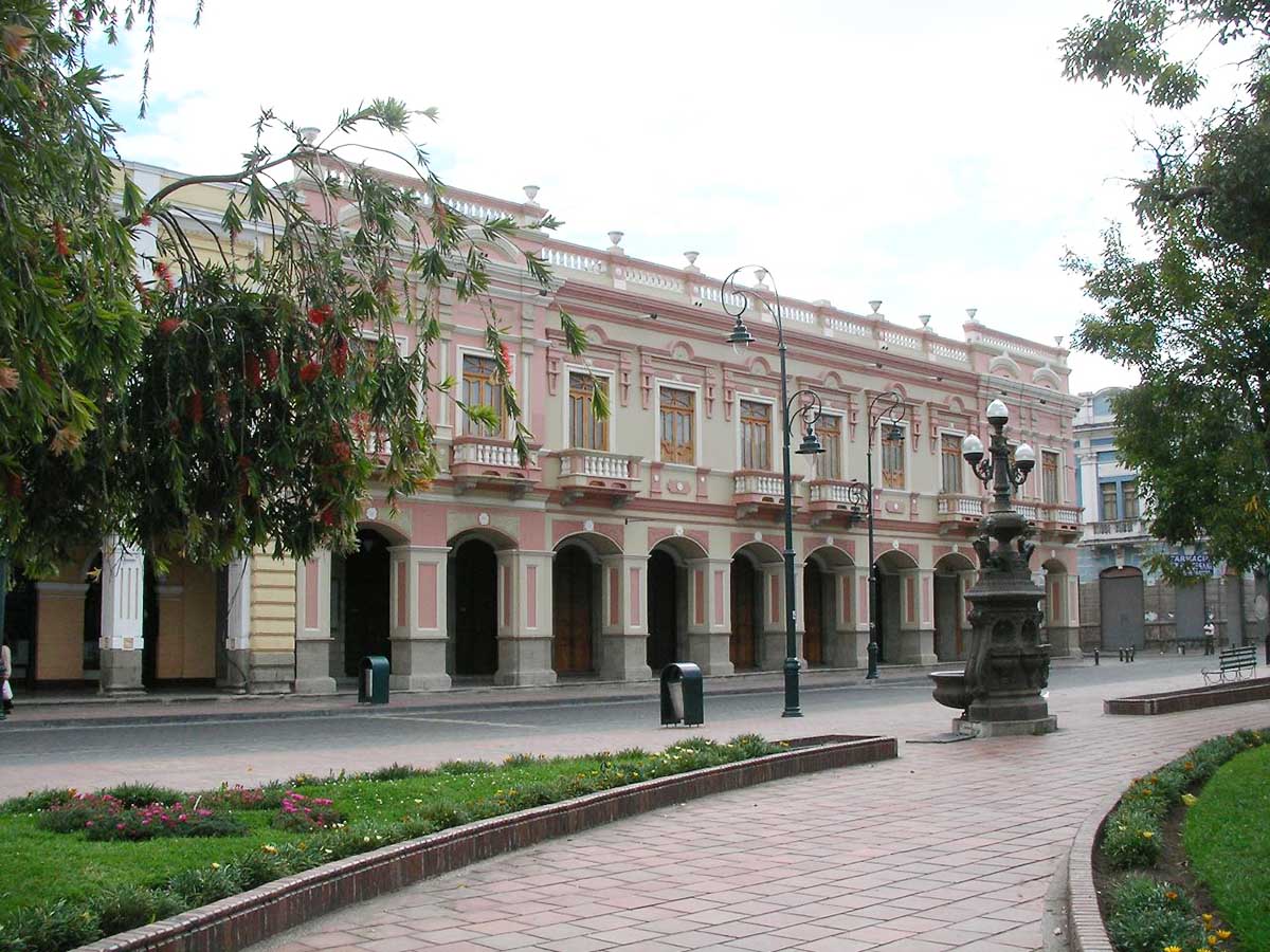 A pink-hued building with an arched arcade on the first level in Riobamba, Ecuador.