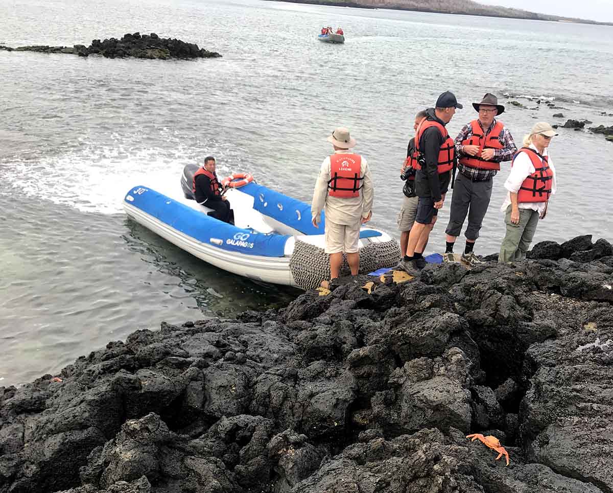 A dinghy approaches a rough, rocky shore. Add sturdy shoes to your Galapagos packing list!