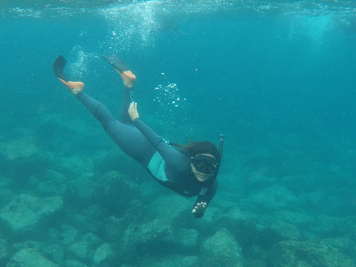 A person in full snorkeling equipment underwater in the Galapagos.