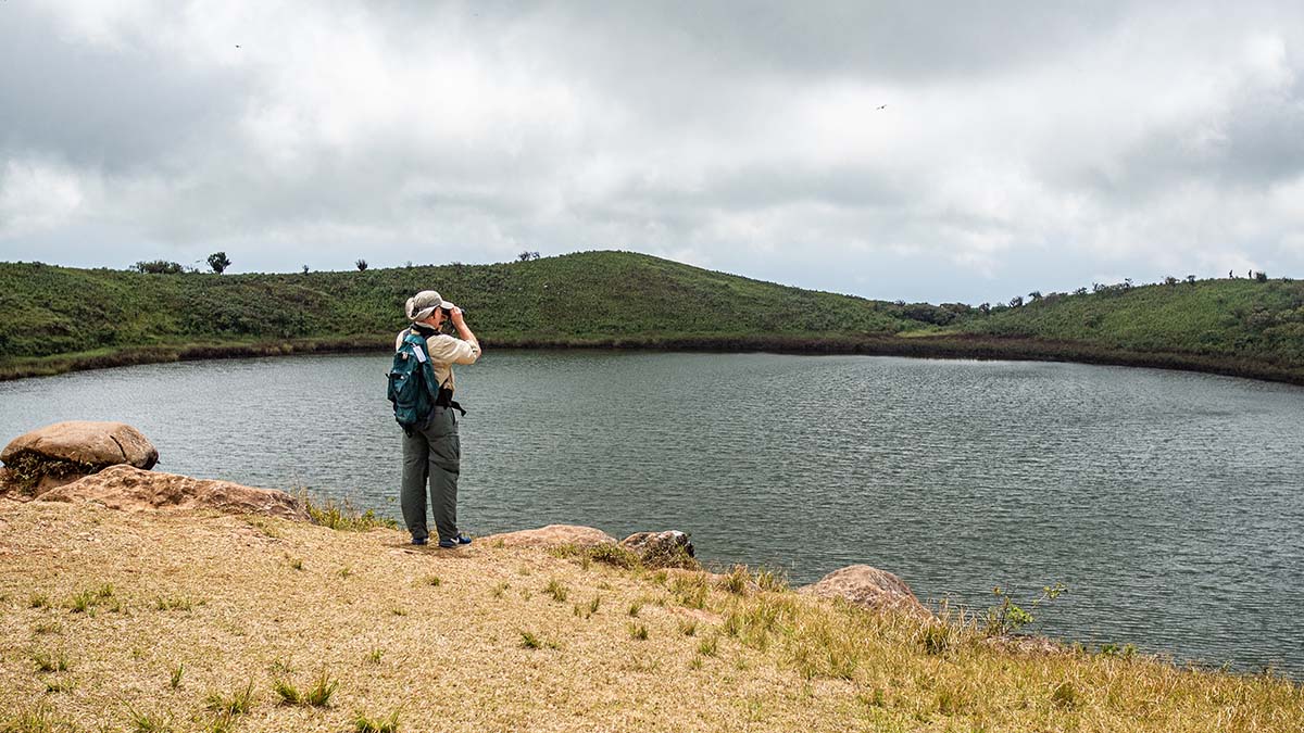 A man with a backpack and binoculars looks over a lagoon in the Galapagos.