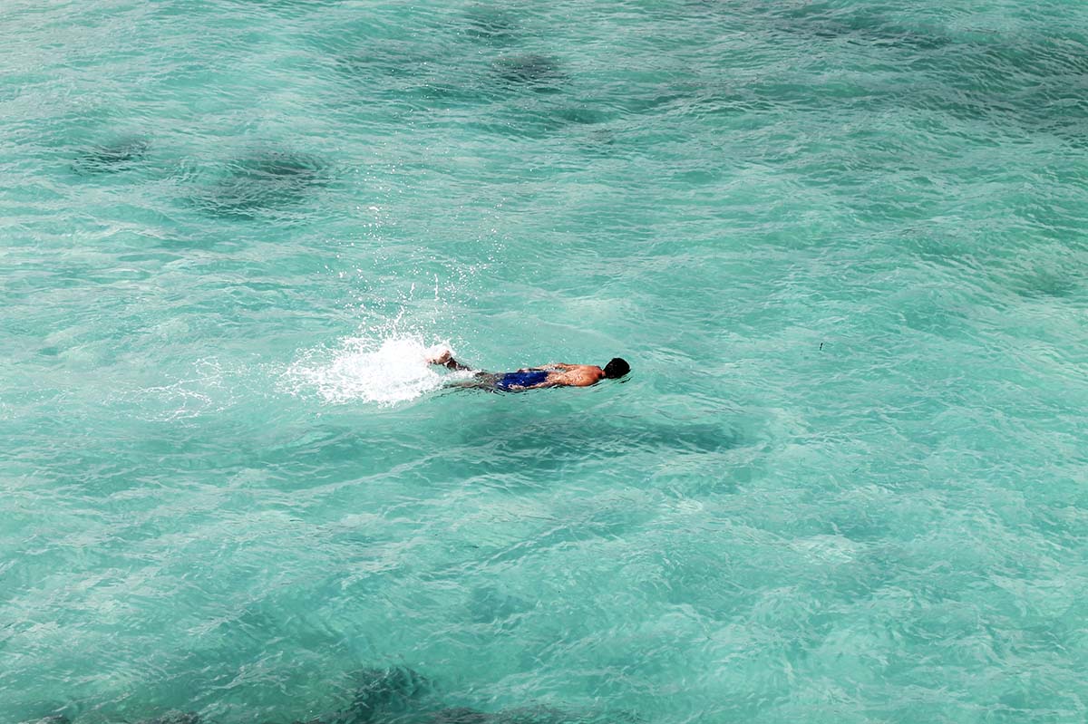 A person swimming in turquoise blue water in the Galapagos.