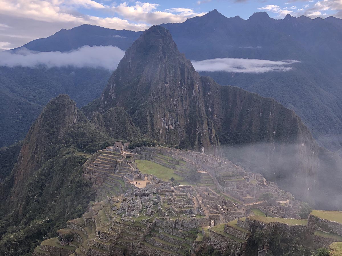 A green mountain peek sits behind the Machu Picchu citadel in South America.