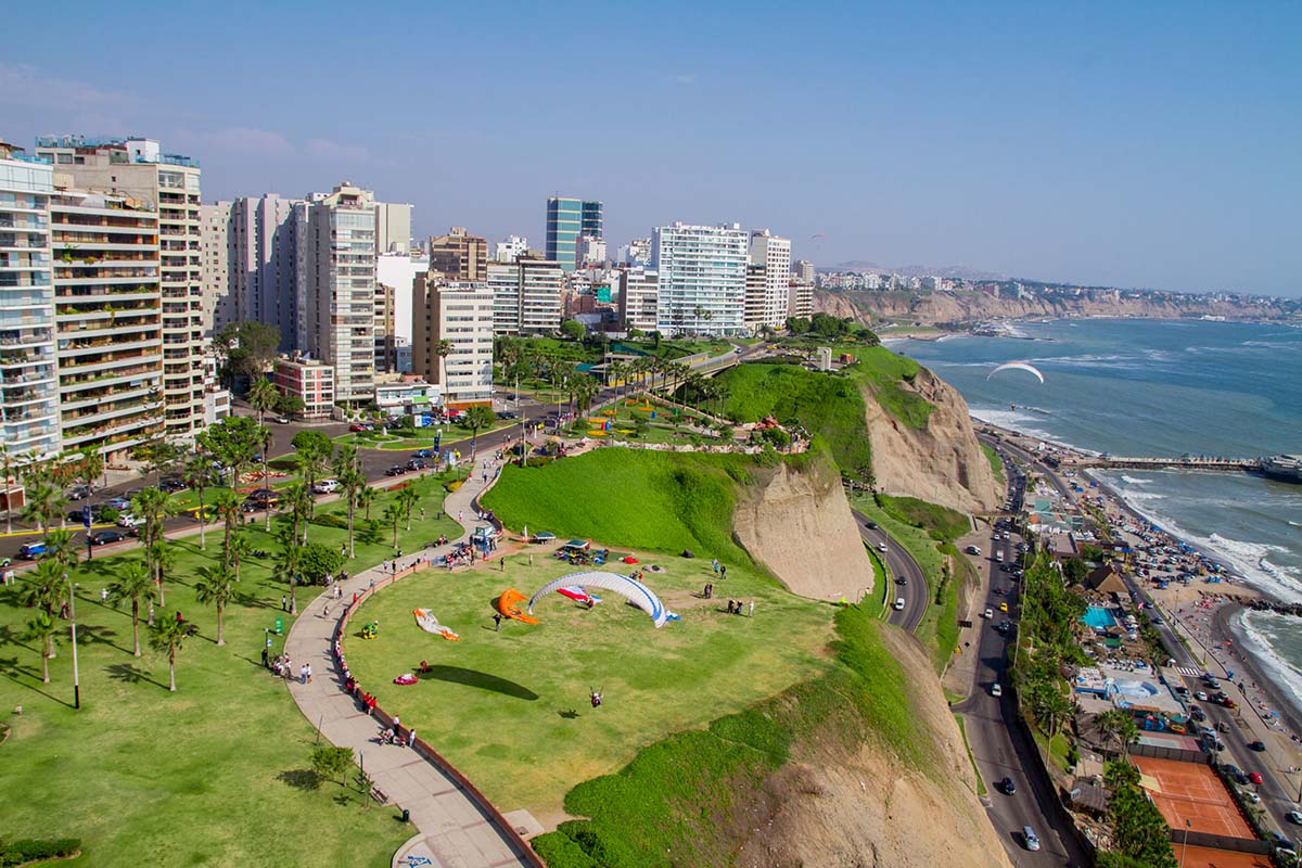 Buildings atop the green cliffs of Lima, Peru. Highway and ocean below the cliffs.