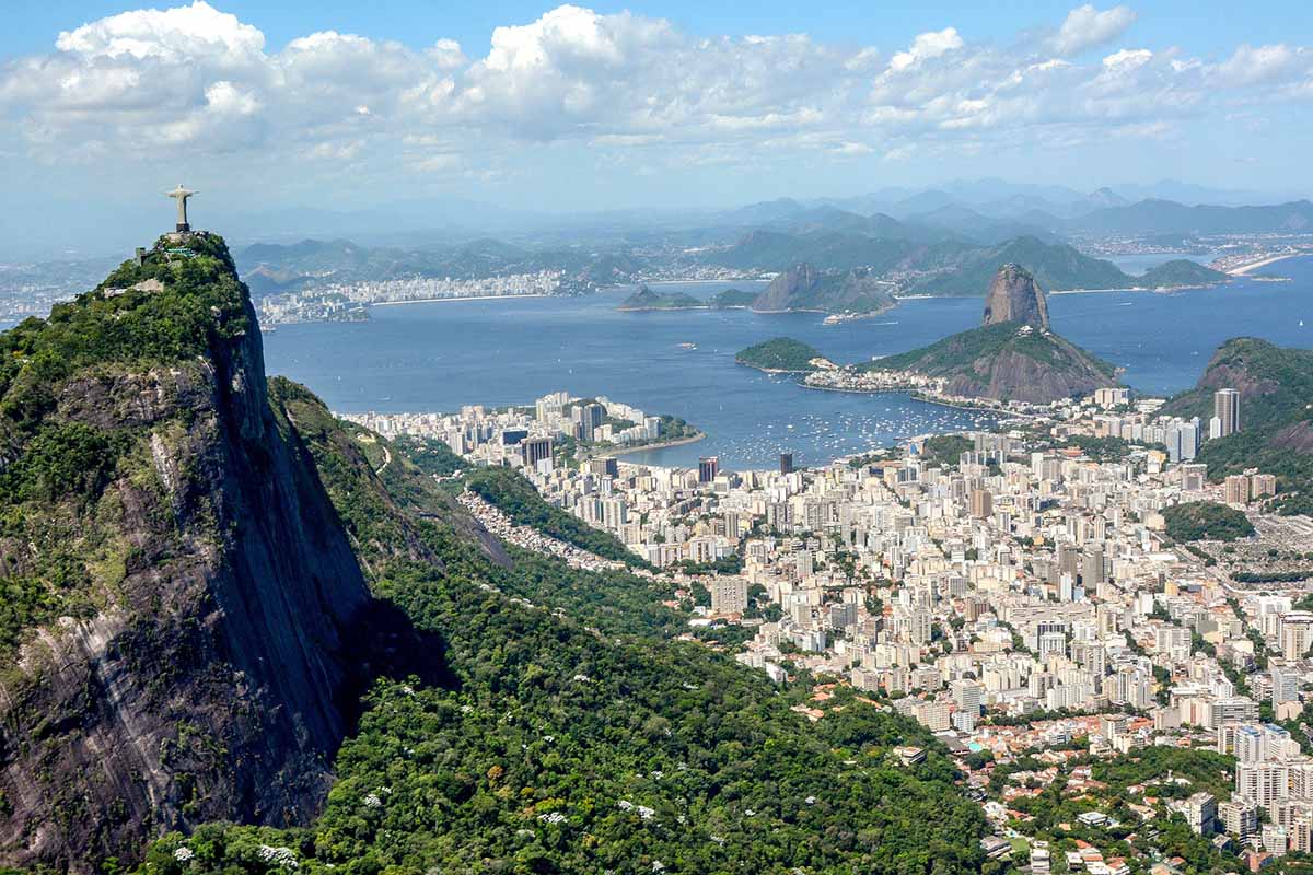 Rio de Janeiro from above, skyscrapers lead up to the sea with several green hills on the outskirts.