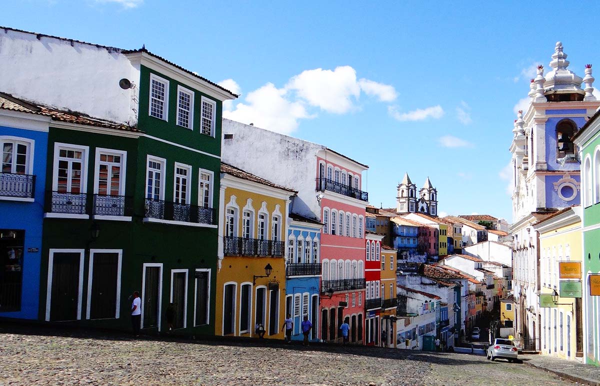 Two and three story building in bright colors on both sides of a road in Salvador de Bahia, Brazil.