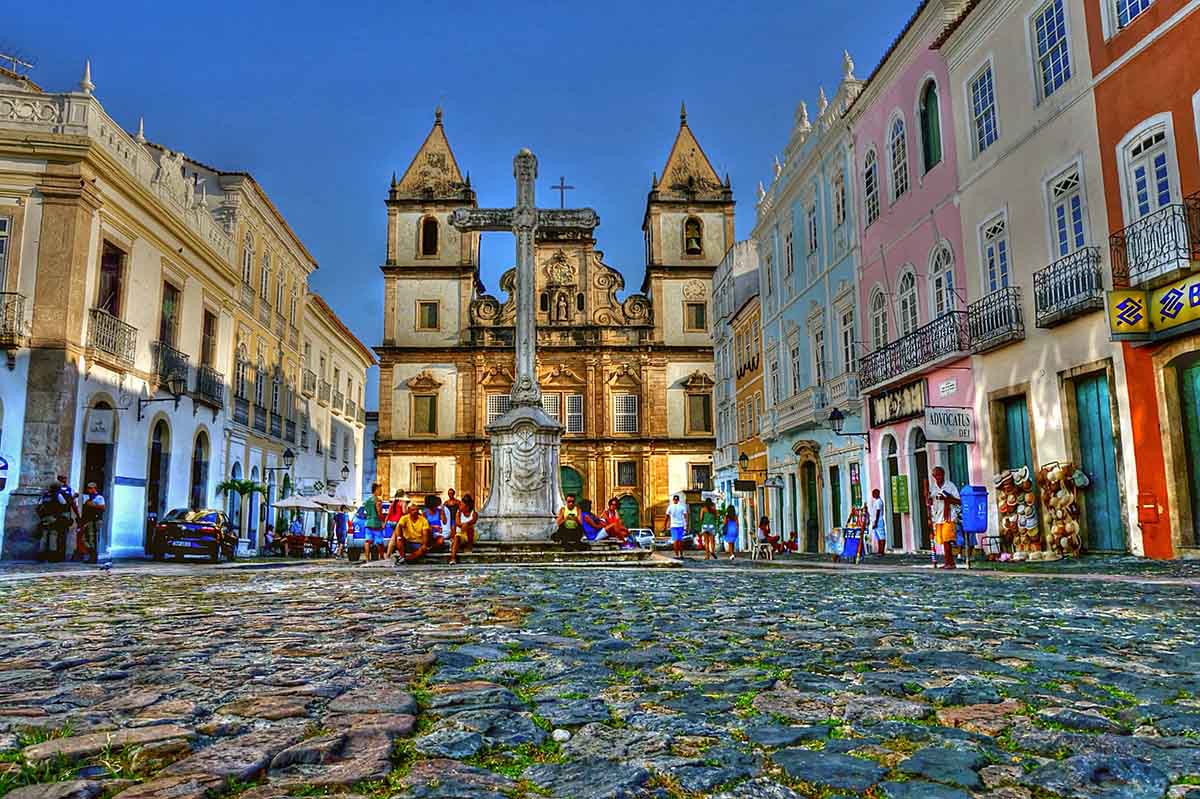 Buildings in an array of colors lead to a cross and church towards the end of the road.