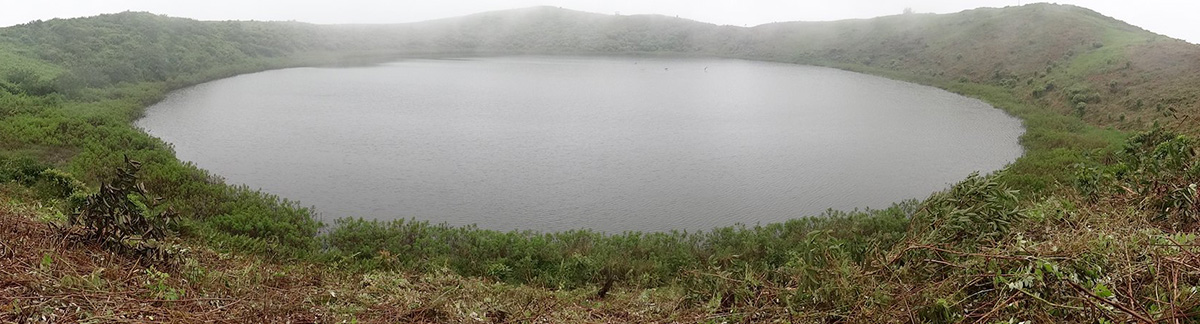 El Junco lagoon, the only freshwater source on San Cristobal Island, with grey mist on a cloudy day.