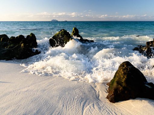 Ocean waves crash onto white sand on one of the galapagos island beaches on Espanola Island.