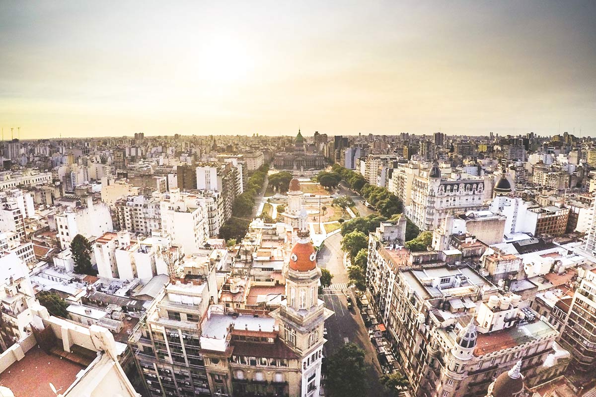 The high rise buildings of a neighborhood in Buenos Aires that surrounds a plaza. 