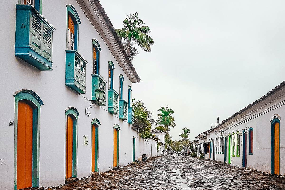 A wide stone street in downtown Paraty that's lines by white colonial-style buildings with colorful trim.