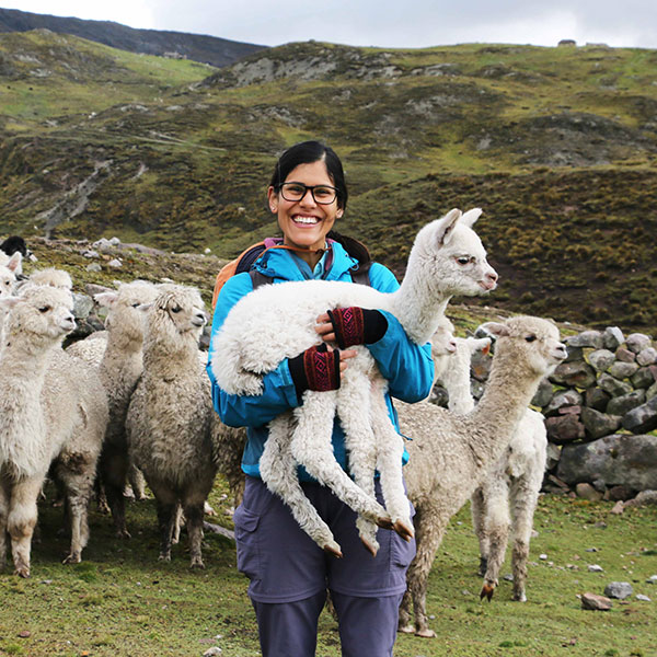 A photo of a woman in a blue jacket with snow covered mountains in the background on our about us page.