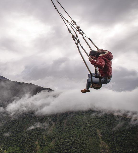 A woman swinging above the cloud forest on the Swing at the End of the World in Baños.