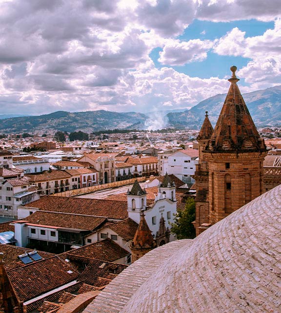 A view of the city of Cuenca on a cloudy day as seen from the roof of a cathedral.