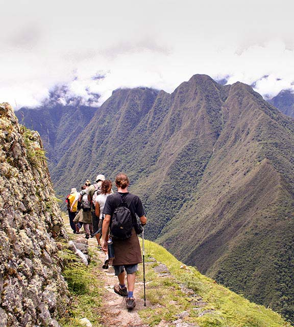 A group of hikers walking past spectacular mountain scenery on the Inca Trail to Machu Picchu.