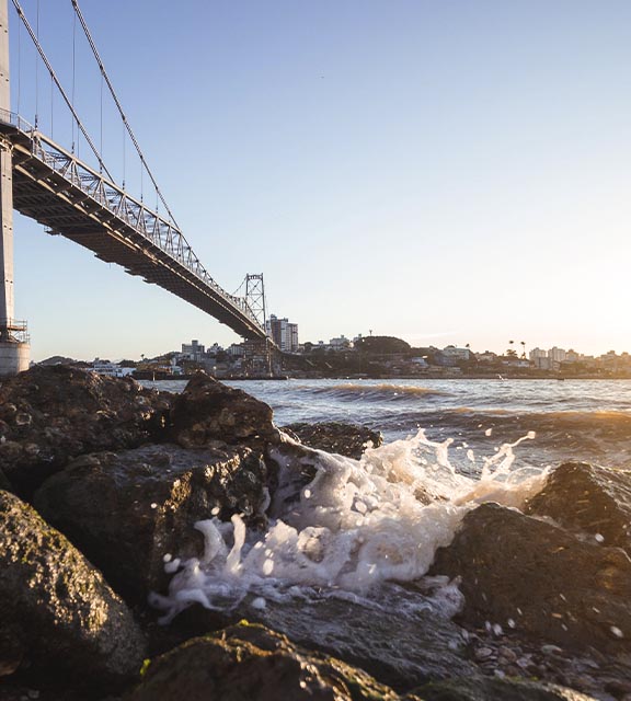 Waves splashing up onto some rocks underneath the Hercílio Luz Bridge in Florianopolis.