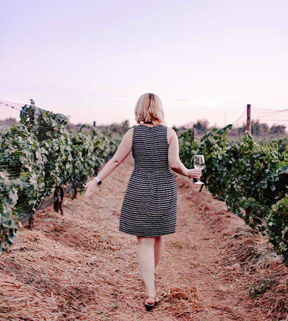 A woman holding a wine glass while walking through a vineyard in Mendoza, Argentina’s wine capital.