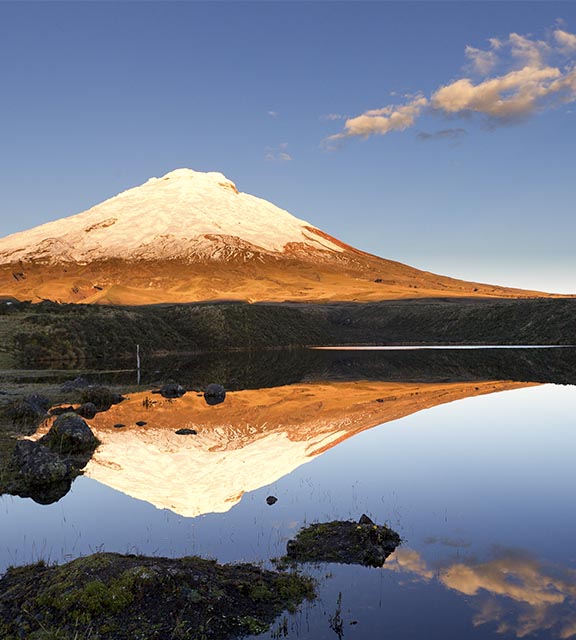The snow-capped Cotopaxi Volcano casting a reflection on a small lake in the Ecuadorian Andes.