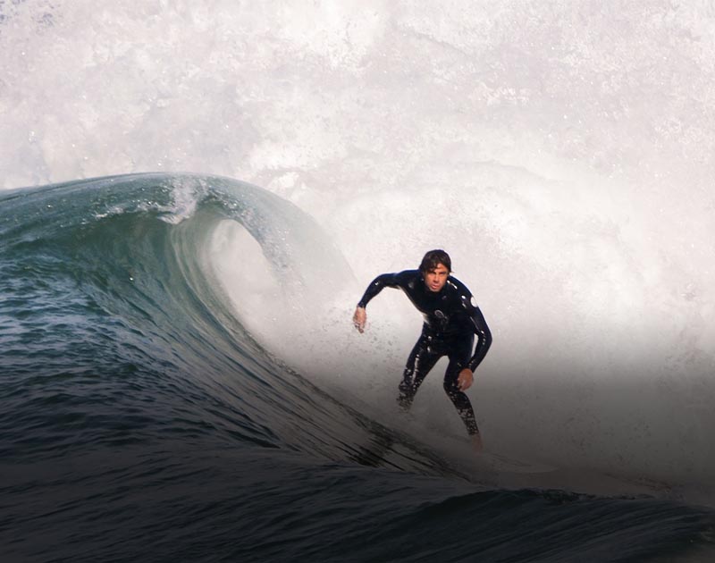 A surfer wearing a wetsuit and catching a wave in the waters off the coast of Arica.