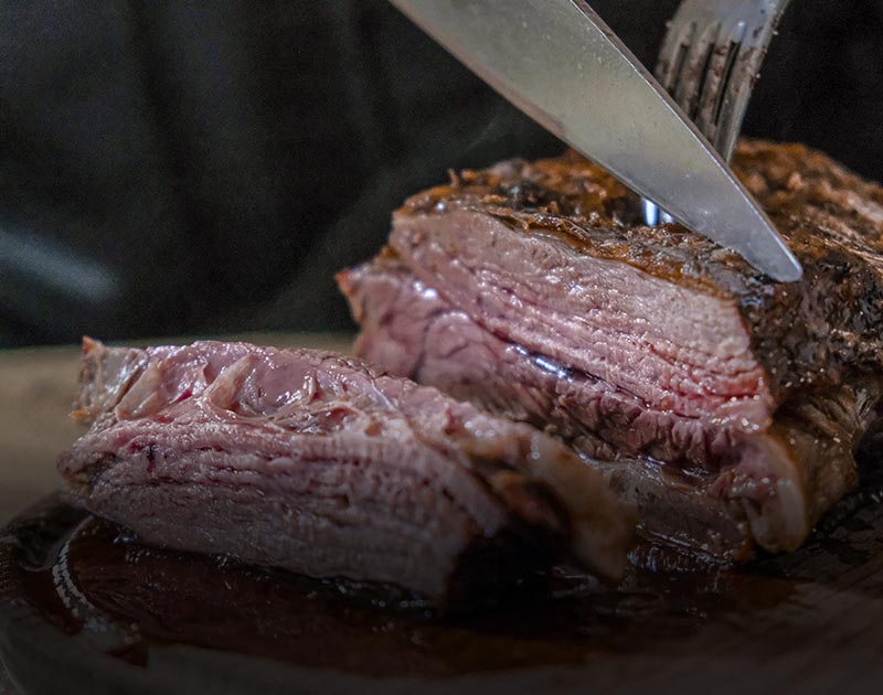 A diner cutting into a piece of steak cooked medium rare, an Argentinian specialty.