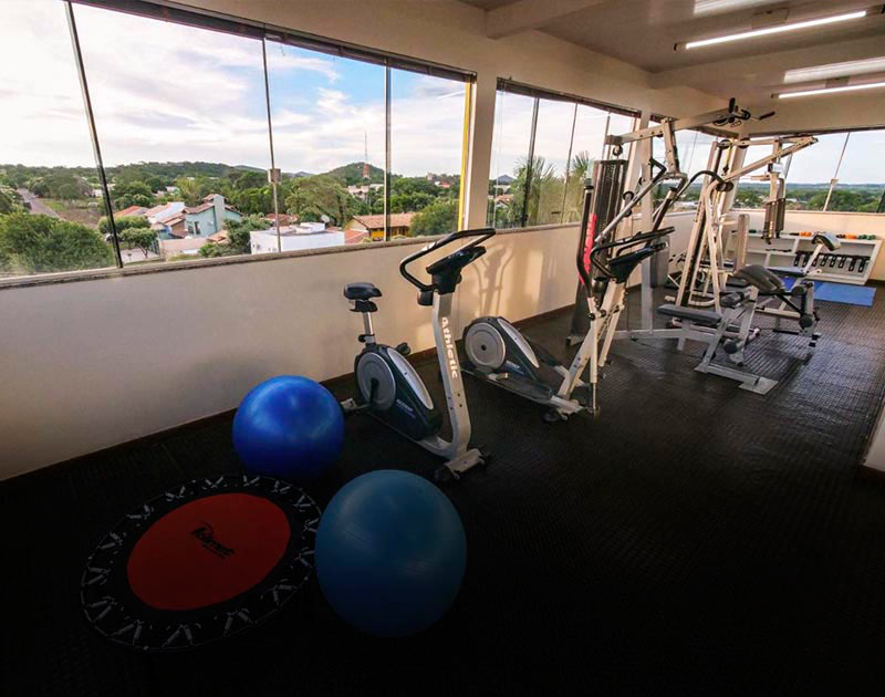 A gym with various exercise equipment and a panoramic view of the surrounding city and landscape.