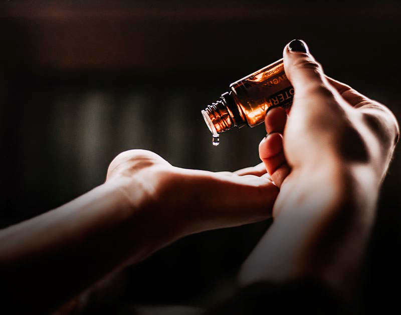 A hand dropping some essential oil on the opposite hand for aromatherapy purposes.