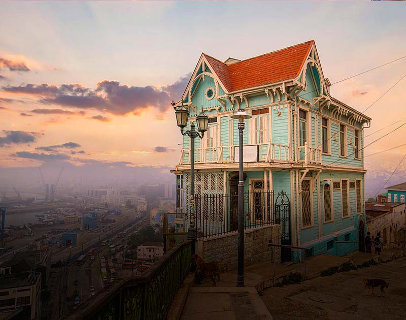 A classic house painted pastel green, situated on a hillside overlooking the city of Valparaiso.