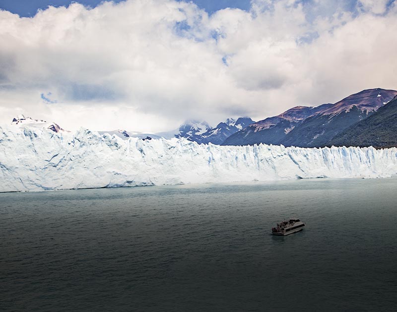 A cruise ship navigating the water next to an enormous glacier near the town of El Calafate.