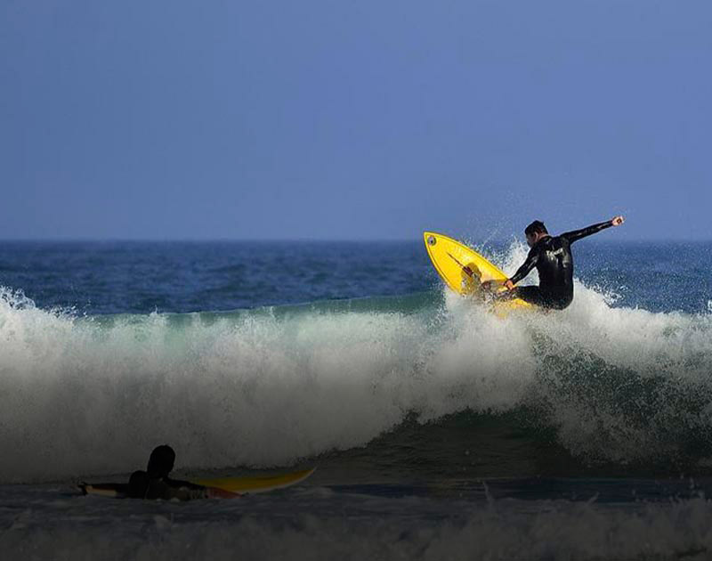 A surfer catching a wave with a yellow surfboard in Florianopolis, a surfer’s paradise in Brazil.