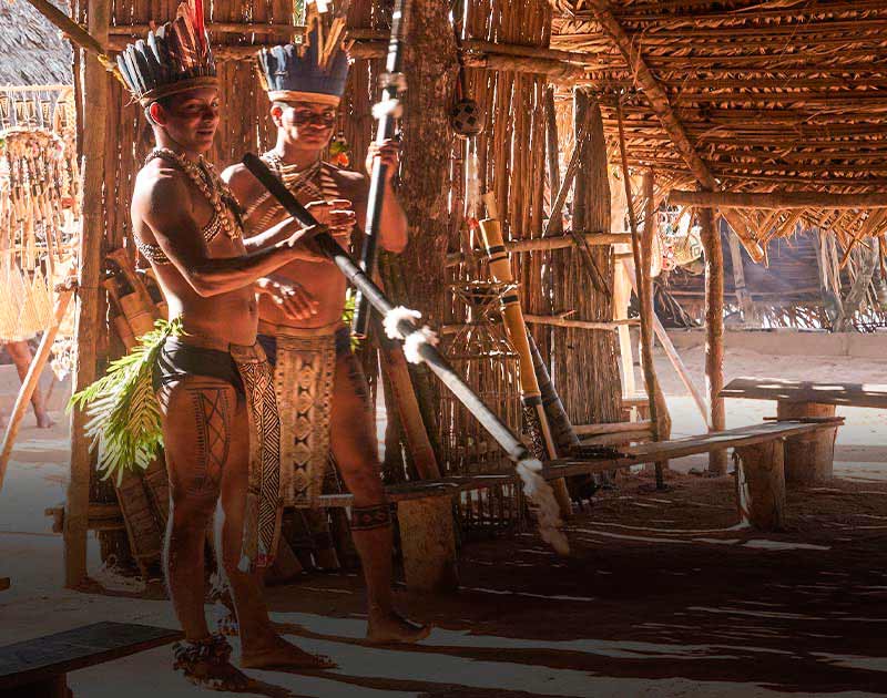 Members of the Desana tribe wearing traditional clothing and holding blowguns in the Amazon.