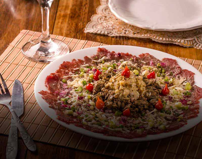 A plate of Brazilian carpaccio topped with various vegetables at a restaurant in Ouro Preto.