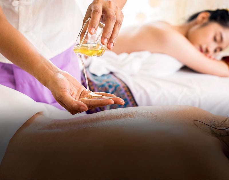 A massage therapist pouring oil into their hand to rub on a client’s back at a wellness center.