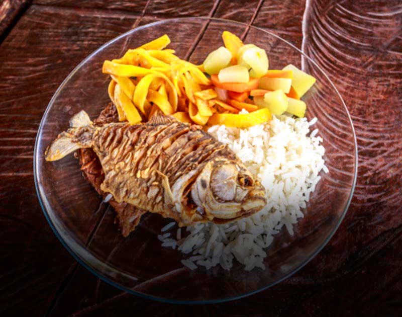 A plate with a fried piranha fish, a side of rice, and vegetables at a restaurant in the Pantanal.