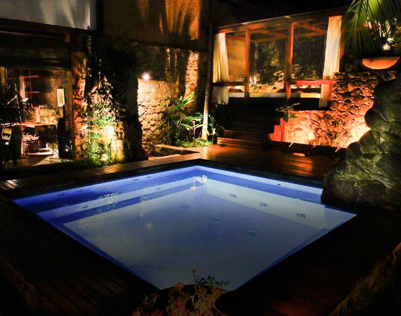 A small illuminated pool surrounded by a wooden deck at the luxurious Casa Turquesa in Paraty.