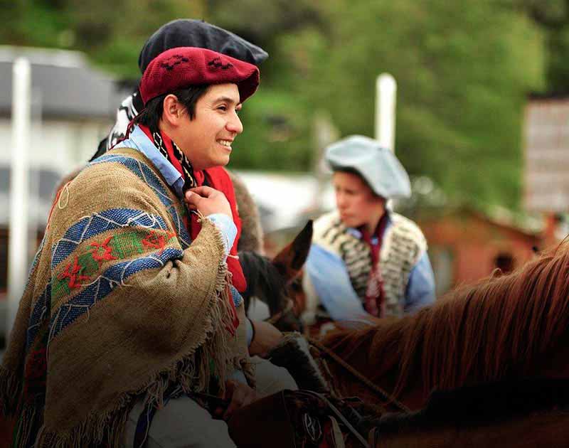 A man on horseback wearing the traditional clothing of a gaucho, or Argentine cowboy.