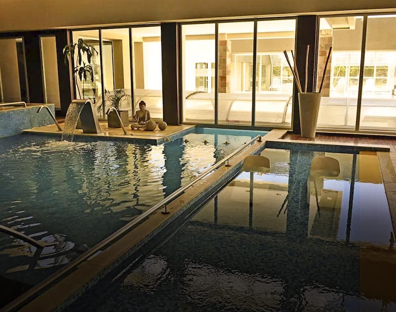 An indoor pool at the Rayentray Hotel, surrounded by various decorations including a buddha statue.