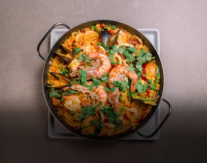 A pot of paella, a dish of Spanish origin featuring rice and an assortment of different seafood.