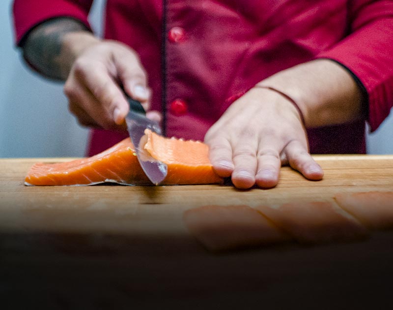 A chef cutting a filet of salmon on a wooden cutting board at a restaurant in Puerto Montt.