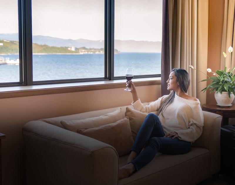 A woman relaxing on a sofa with a glass of wine at the Hotel Gran Pacifico in Puerto Montt.