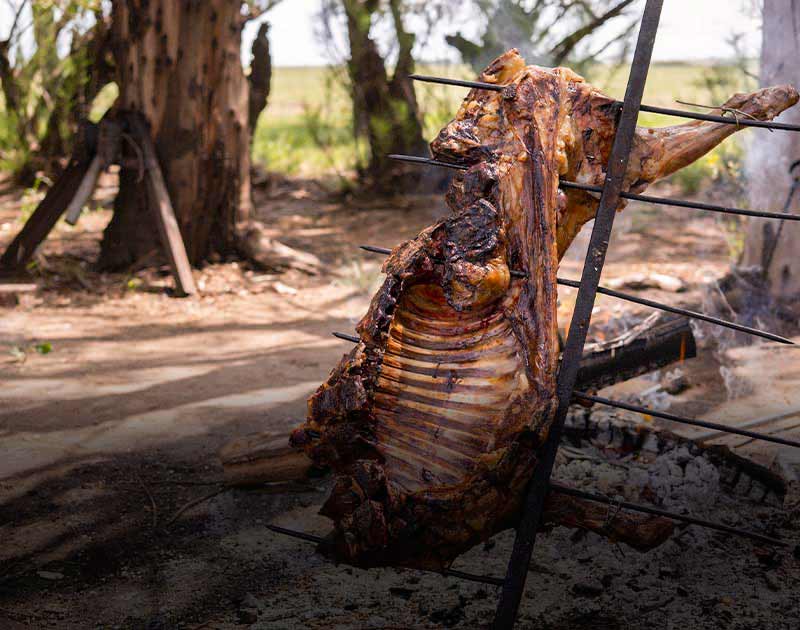A rack of lamb being cooked on a spit over a fire at an outdoor location near Puerto Natales.