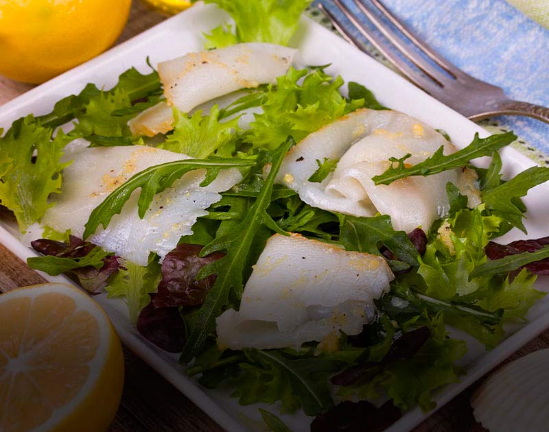 A plate with Patagonian toothfish, green salad and lemon at a restaurant in Punta Arenas.