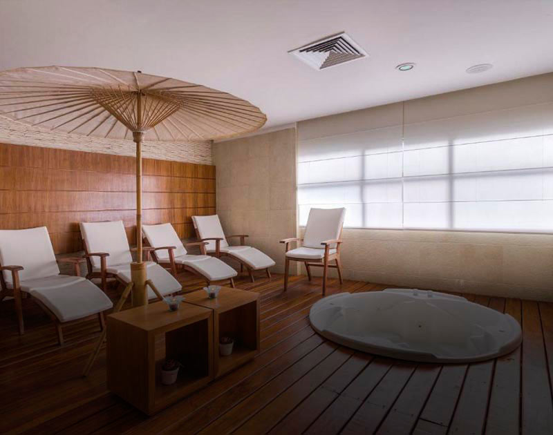 Chaise longues and an umbrella on a wooden deck next to a jacuzzi at the Grand Mercure Recife.