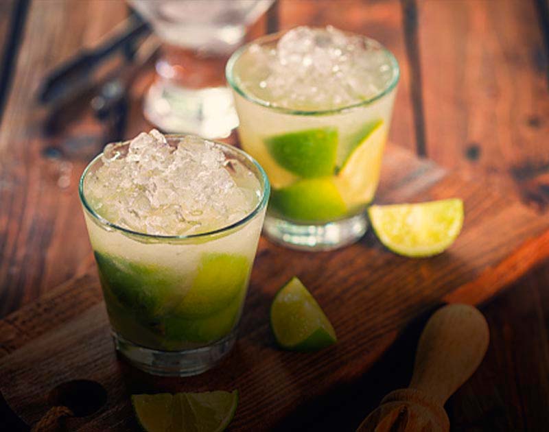 A cutting board with two caipirinhas, a typical Brazilian cocktail with cachaça, sugar and lime.