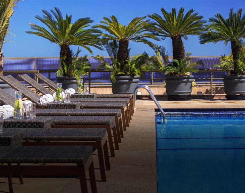 Chairs next to a pool surrounded by tropical palm trees at the JW Marriott in Rio de Janeiro.