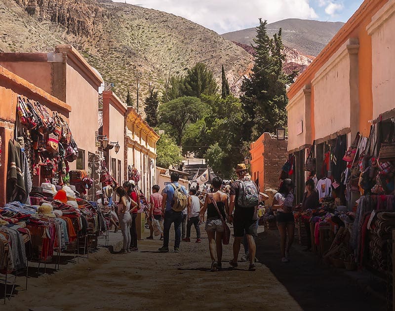 Visitors browsing an outdoor artisan market in Salta with clothing and other items for sale.