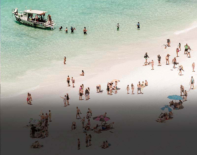 Crowds of people enjoying Flamengo Beach in Salvador, with a boat anchored just offshore.